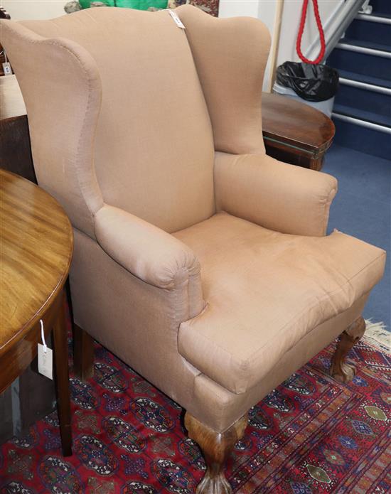 A George III design upholstered wing armchair on ball and claw feet